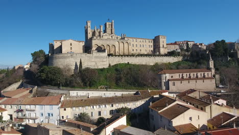 Aerial-track-toward-Béziers-Cathedral-bue-sky,-roof-houses